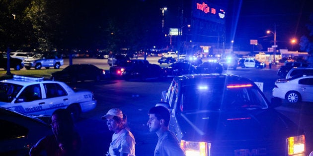 Bystanders look on as emergency personnel respond to the scene of a deadly shooting at the Grand Theatre in Lafayette, La., Thursday, July 23, 2015. (AP Photo/Denny Culbert)