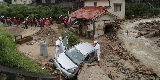 流された車両を調べる広島県警の警察官（手前）ら＝7月8日午前、広島市東区馬木