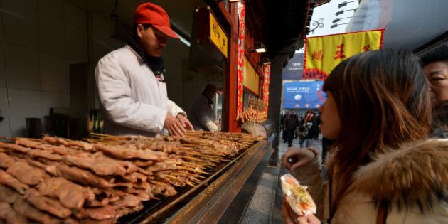 A Chinese hawker barbecues lamb kebabs at his stall in the Wangfujing shopping street of Beijing on February 21, 2013. China is considering a ban on barbecues to help reduce air pollution in built-up areas after heavy smog recently choked large swathes of the country, state media reported. The country's environmental watchdog has issued draft guidelines advising major cities to adopt legislation banning 'barbecue-related activities', risking the ire of street food-loving locals. AFP PHOTO/Mark RALSTON (Photo credit should read MARK RALSTON/AFP/Getty Images)