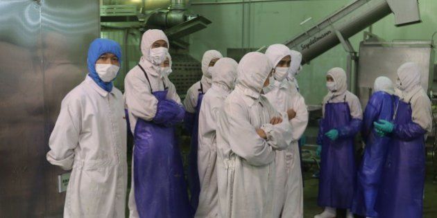 This picture taken on July 20, 2014 shows workers standing aside as inspectors investigate the Shanghai Husi Food Co., a factory of US food provider OSI Group, in Shanghai. Shanghai city officials have shut a Shanghai Husi factory of US food provider OSI Group for selling out-of-date meat to restaurant giants including McDonald's and KFC, authorities said on July 21 in China's latest food safety scandal. CHINA OUT AFP PHOTO (Photo credit should read STR/AFP/Getty Images)