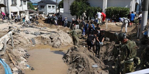 自衛隊員と川底にたまった土砂を取り除く人たち＝7月11日、広島市安芸区