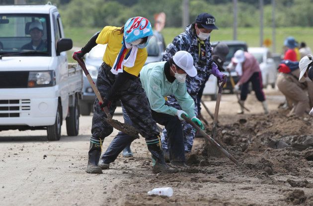 水が引いた真備町地区で、道路に残った泥をかき出す人たち＝１０日、岡山県倉敷市 撮影日：2018年07月10日