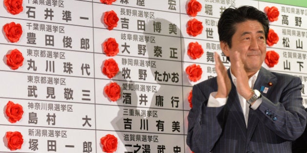 Japanese Prime Minister and President of the Liberal Democratic Party (LDP), Shinzo Abe celebrates his party's win after he placed a red paper rose on a LDP candidate's name to indicate an election victory at the party's headquarters in Tokyo on July 21, 2013. Voters gave Prime Minister Shinzo Abe a resounding victory in upper house elections July 21, exit polls showed, likely ushering in a new period of stability for politically volatile Japan. AFP PHOTO / KAZUHIRO NOGI (Photo credit should read KAZUHIRO NOGI/AFP/Getty Images)