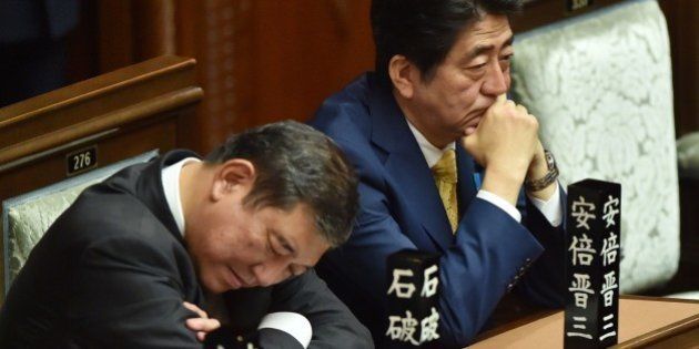 Japan's Prime Minister Shinzo Abe (R) and Regional Revitalization Minister Shigeru Ishiba (L) listen to a speech by a member of an opposition party during a lower house plenary session at the parliament in Tokyo on July 16, 2015. Controversial security bills that opponents say will undermine 70 years of pacifism and could see Japanese troops fighting abroad for the first time since World War II, passed through the powerful lower house of parliament on July 16. AFP PHOTO / KAZUHIRO NOGI (Photo credit should read KAZUHIRO NOGI/AFP/Getty Images)