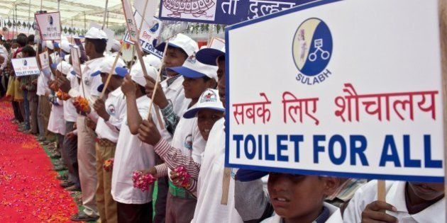 Indian schoolchildren hold placards as they welcome Bindeshwari Pathak, founder and chairman of NGO Sulabh International, at Katra Sahadatgunj village in Badaun on August 31, 2014. More than 100 new toilets were unveiled August 31 in a poverty-stricken and scandal-hit village in northern India, where fearful and vulnerable women have long been forced to defecate in the open. Sanitation charity Sulabh International handed over the brightly coloured structures to cheering villagers in Uttar Pradesh state, just weeks after Prime Minister Narendra Modi announced every household should have a toilet within four years. More than 500 million Indians defecate outdoors, according to the World Bank, particularly in poor, rural areas such as Badaun district in Uttar Pradesh, leaving them exposed to diseases. AFP PHOTO/Prakash SINGH (Photo credit should read PRAKASH SINGH/AFP/Getty Images)