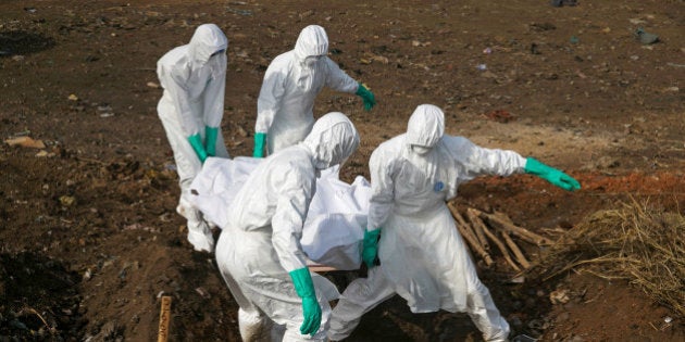 Health workers carry the body of a suspected Ebola victim for burial at a cemetery in Freetown, Sierra Leone, December 21, 2014. To match Special Report HEALTH-WHO/LEADER REUTERS/Baz Ratner/File Photo