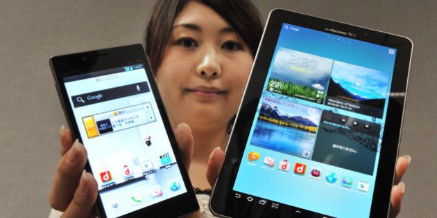 A model displays a new high-spec smartphone 'Optimus G L-01E' (L) and the world's largest organic EL display at 7.7 inches tablet 'GALAXY Tab 7.7 Plus SC-01E' (R) by Japanese mobile phone carrier NTT DoCoMo during a press preview in Tokyo on August 28, 2012. NTT DoCoMo unveiled three new smartphones and two new tablets, all compatible with the company's Xi LTE mobile service, for launch in or after September. AFP PHOTO / KAZUHIRO NOGI (Photo credit should read KAZUHIRO NOGI/AFP/GettyImages)