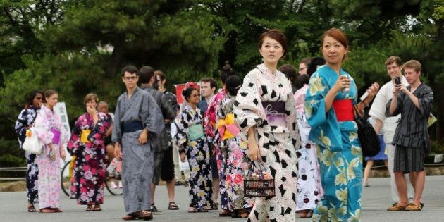 HIMEJI, JAPAN - JUNE 22: Japanese women dressed in Yuakata, a summer kimono ,walk as foreigners dressed in Yukata take photographs during the annual Himeji Yukata Festival on on June 22, 2014 in Himeji, Japan. Yukata is a casual summer version of kimono, traditionally made of cotton instead of silk. The Himeji Yukata Festival was started by Himeji lord Sakakibara Masamune over 250 years ago. (Photo by Buddhika Weerasinghe/Getty Images)
