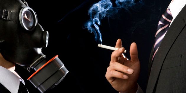 Man wearing gas mask standing by smoking man