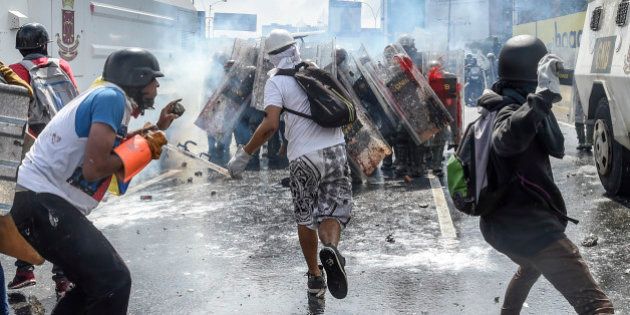 Opposition activists and riot police clash during a protest against President Nicolas Maduro in Caracas, on May 10, 2017.Venezuelan protesters hit the streets on Wednesday armed with 'Poopootov cocktails,' jars filled with excrement which they vowed to hurl at police as a wave of anti-government demonstrations turned dirty. / AFP PHOTO / JUAN BARRETO (Photo credit should read JUAN BARRETO/AFP/Getty Images)