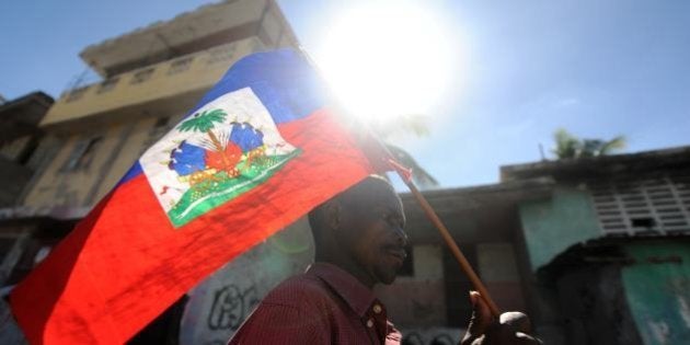 A man holds a Haitian flag as he takes part in a protest demanding that Haitian President Michel Martelly step down in Port-au-Prince on January 13, 2014. The protesters walked from one sector of the center of the capital to the parliament, where Martelly was to deliver a speech on the country's political and economic situation. AFP PHOTO/Hector RETAMAL (Photo credit should read HECTOR RETAMAL/AFP/Getty Images)