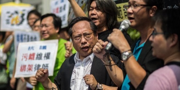 Hong Kong Democratic Party's Albert Ho (C) wears mock handcuffs as he and legislator Leung Kwok-hung (top C), known as 'Long Hair', attend a protest in Hong Kong on July 12, 2015, after at least 50 Chinese human rights lawyers and activists were detained or questioned in recent days in an 'unprecedented' police swoop, rights groups said on July 11, with around 20 still feared to be held. The scale of the clampdown on the legal profession began to emerge when a friend of lawyers and staff at a single Beijing law firm known for its human rights casework said at least five had been detained in the last couple of days. AFP PHOTO / ANTHONY WALLACE (Photo credit should read ANTHONY WALLACE/AFP/Getty Images)