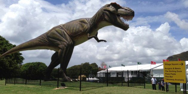 FILE - In this Dec. 11, 2012 file photo, people stand near an eight-meter (26-foot) replica of a tyrannosaurus rex standing between the 9th green and the 10th tee at the Sunshine Coast resort course in south Queensland, Australia. The PGA of Australia confirmed, Monday, Feb. 11, 2013, it will move the venue of its PGA Championship, which was overshadowed last year by the billionaire resort owner's decision to position a giant robotic dinosaur outside the clubhouse and post unusual signage around the course. (AP Photo/Dennis Passa, File)