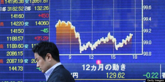 A pedestrian walks past an electronic stock board displaying a chart of the yen against the U.S. dollar outside a securities firm in Tokyo, Japan, on Tuesday, May 7, 2013. The Topix Index climbed the most in a month, erasing losses from the 2008 collapse of Lehman Brothers Holdings Inc., as Japanese markets reopened from a holiday during which the yen slid and U.S. jobs data beat estimates. Photographer: Junko Kimura/Bloomberg via Getty Images