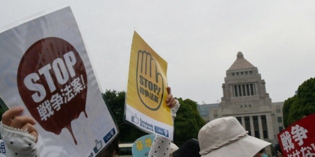 A protester holds banners which translate as 'Stop Military Bills' while attending a protest rally against a security bill outside the Diet building in Tokyo on June 14, 2015. Almost 25,000 protesters gathered around the Diet building to oppose a controversial bill for Japan's growing security engagement. AFP PHOTO / TOSHIFUMI KITAMURA (Photo credit should read TOSHIFUMI KITAMURA/AFP/Getty Images)