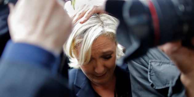 Marine Le Pen, French National Front (FN) party candidate for 2017 presidential election, is protected by bodyguards as eggs are thrown by demonstrators during her arrival in Dol-de-Bretagne, France, May 4, 2017. REUTERS/Stephane Mahe