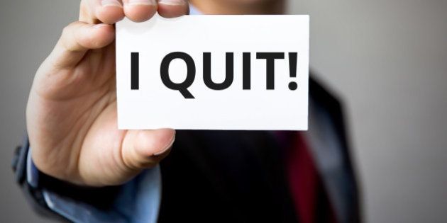 Businessman presenting 'I Quit' word on white card.