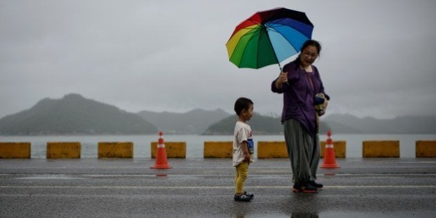 TO GO WITH Skorea-accident-boat-family,FEATURE by Jung Ha-WonIn a photo taken on July 6, 2014 a woman and child walk in Jindo harbour, where families of the victims of the Sewol ferry still unaccounted for continue to wait. Eleven families are maintaining a bitter, defiant vigil in Jindo, as divers continue the increasingly desperate, dangerous search for the last remaining bodies trapped in the sunken vessel. Just over 300 people died, the vast majority high school students on an organised outing. A total of 172 were rescued before the ferry sank and a massive recovery effort involving hundreds of divers working in near zero visibility has since retrieved 293 bodies. AFP PHOTO / Ed Jones (Photo credit should read ED JONES/AFP/Getty Images)