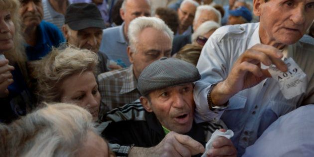 Pensioners holding their queue numbers try to enter into a bank in Athens, Wednesday, July 1, 2015. About 1,000 bank branches around the country were ordered by the government to reopen Wednesday to help desperate pensioners without ATM cards cash up to 120 euros ($134) from their retirement checks. Eurozone finance ministers were set to weigh Greece's latest proposal for aid Wednesday. (AP Photo/Daniel Ochoa de Olza)