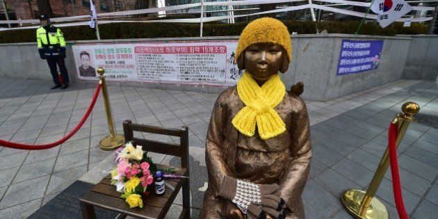 A South Korean policeman (L) stands guard near a statue (C) of a teenage girl in traditional costume called the 'peace monument' for former 'comfort women' who served as sex slaves for Japanese soldiers during World War II, in front of the Japanese embassy in Seoul on December 29, 2015. South Korean officials met with former 'comfort women' to seek their support for a landmark deal with Japan, after criticism it does not properly atone for the treatment of women forced into WWII army brothels. AFP PHOTO / JUNG YEON-JE / AFP / JUNG YEON-JE (Photo credit should read JUNG YEON-JE/AFP/Getty Images)