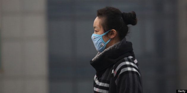 A woman wears a mask as she walks on a street in Beijing, China, on Friday, March 15, 2013. China's new premier promised to crack down on corruption and clean up pollution, acknowledging the need to tackle two issues that have stoked public anger toward the country's leaders. Photographer: Tomohiro Ohsumi/Bloomberg via Getty Images