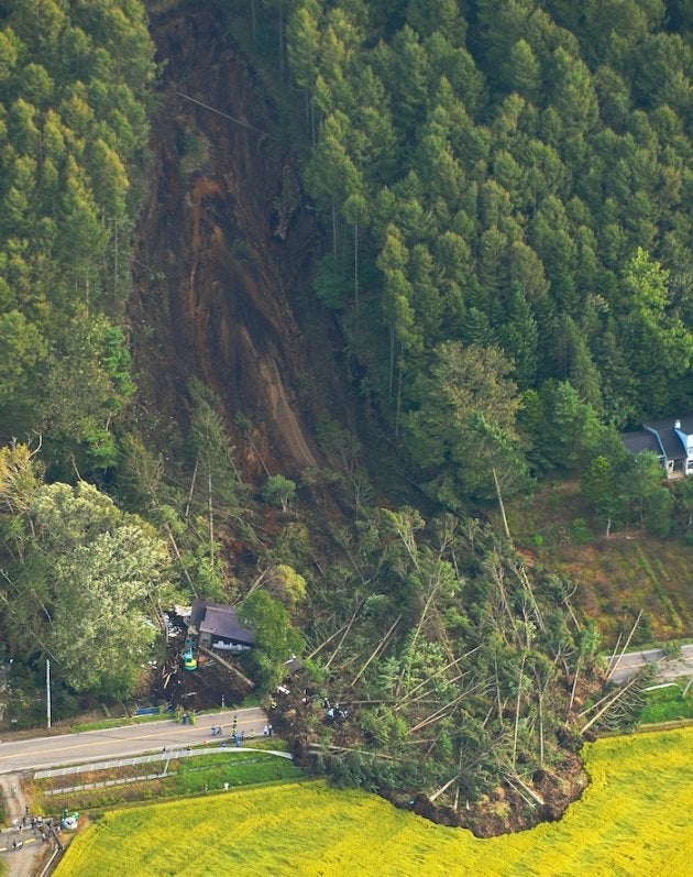 地震で発生した大規模な土砂崩れの現場。左下は倒壊した家屋周辺で行われている捜索＝北海道厚真町上空