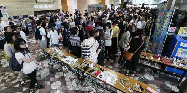 携帯電話の充電を待ち、市役所ロビーを埋め尽くす人たち＝9月6日午後、札幌市中央区