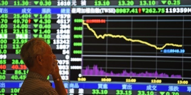 A man speaks in front of monitors showing market movements at the Taiwan Stock Exchange in Taipei on July 8, 2015. Taiwan's weighted index fell 274.05 points or 2.96 percent to 8,976.11 as a rout in China spread into regional markets while traders are also buffeted by fears about Greece's future in the eurozone. AFP PHOTO / Sam Yeh (Photo credit should read SAM YEH/AFP/Getty Images)