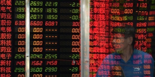 An investor is reflected in a glass window in front of a screen displaying share prices at a security firm in Shanghai on July 6, 2015. Shanghai stocks were up 2.15 percent at midday on July 6 after the government unveiled its biggest package of measures so far to shore up the slumping market, but an initial surge was pared as analysts questioned their effect. CHINA OUT AFP PHOTO (Photo credit should read STR/AFP/Getty Images)