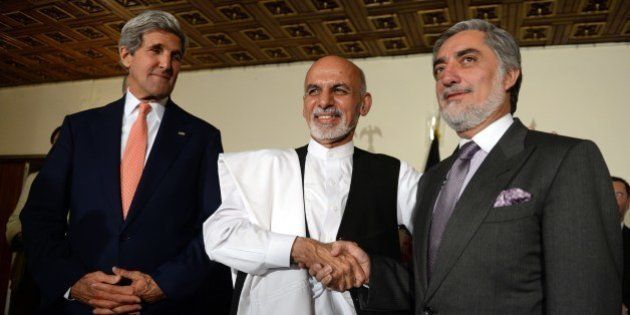 US Secretary of State John Kerry (L) looks at Afghan presidential candidates Ashraf Ghani (C) and Abdullah Abdullah (R) shaking hands, after a joint press conference in Kabul on July 12, 2014. US Secretary of State John Kerry on July 12 held a second day of talks with Afghanistan's feuding presidential hopefuls, seeking a deal to 'clean up the tally' after disputed elections. AFP PHOTO/SHAH MARAI (Photo credit should read SHAH MARAI/AFP/Getty Images)