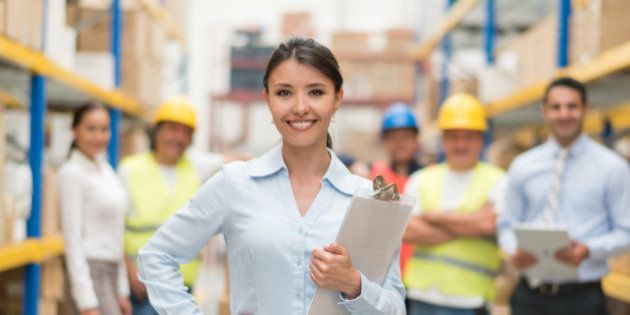 Business woman working at a warehouse with a group of people - freight transportation concepts