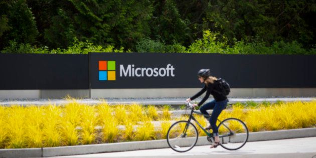 A woman rides a bicycle past a Microsoft Corp. sign on the company's main campus in Redmond, Washington, U.S., on Wednesday, July 17, 2014. Microsoft Corp. said it will eliminate as many as 18,000 jobs, the largest round of cuts in its history, as Chief Executive Officer Satya Nadella integrates Nokia Oyj's handset unit and slims down the software maker. Photographer: Mike Kane/Bloomberg via Getty Images