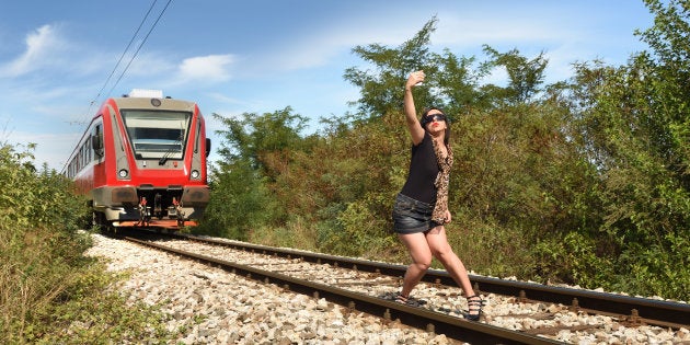 近づく列車の前で自撮りする女性（イメージ写真）