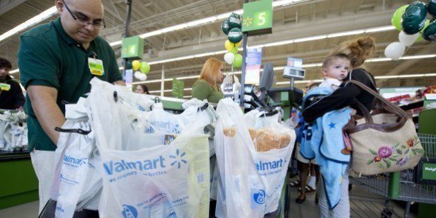 Customer service manager David Cuevas packs items into plastic shopping bags as a customer pays at the cash register on the opening day of the new Walmart Neighborhood Market in Panorama City, California, a working class area about 13 miles (20km) northwest of Los Angeles, on September 28, 2012. Smaller than Walmart's SuperCenter, the Neighborhood Market resembles a traditional supermarket, selling food, health and beauty products and home cleaning supplies. AFP PHOTO / Robyn Beck (Photo credit should read ROBYN BECK/AFP/GettyImages)