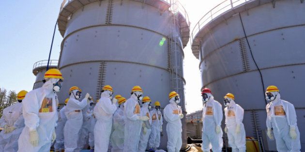 Shinzo Abe, Japan's prime minister, third right wearing a red helmet, is briefed by Akiro Ono, plant chief for the Tokyo Electric Power Co. (Tepco) Fukushima Dai-ichi nuclear power plant, as they stand in front of storage tanks for radioactive water at the Tepco Fukushima Dai-ichi nuclear power plant in Okuma, Fukushima Prefecture, Japan, on Thursday, Sept. 19, 2013. Abe on a visit to the wrecked Fukushima Dai-Ichi atomic station told Tokyo Electric Power Co. its priority is to halt leaks of radioactive water from the plant into the ocean. Source: Japan Pool via Bloomberg