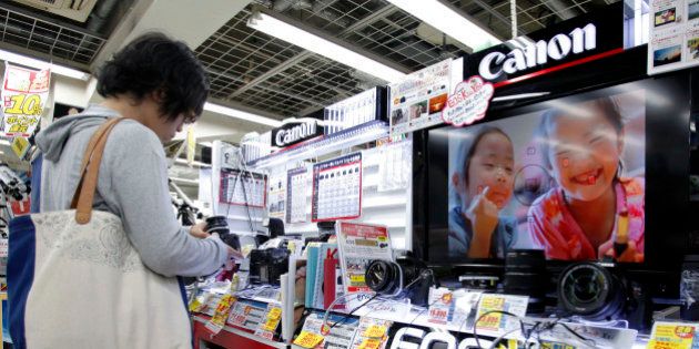A customer looks at Canon Inc. digital cameras at an electronics store in Tokyo, Japan, on Thursday, Oct. 25, 2012. Canon, the world?s largest camera maker, cut its full-year profit forecast after a sluggish global economy damped sales, China production was disrupted and a stronger yen eroded the value of exports. Photographer: Kiyoshi Ota/Bloomberg via Getty Images