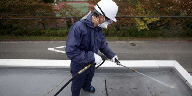 A worker sprays high pressure water during a decontamination process at a kindergarten in Hirono Town,...