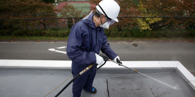 A worker sprays high pressure water during a decontamination process at a kindergarten in Hirono Town, Fukushima Prefecture, Japan, on Monday, Oct. 17, 2011. Japan's environment ministry will budget more than 1.1 trillion yen for decontamination by the end of the next fiscal year, Goshi Hosono, minister in charge of the response to the nuclear crisis, said Sept. 30. Photographer: Tomohiro Ohsumi/Bloomberg via Getty Images