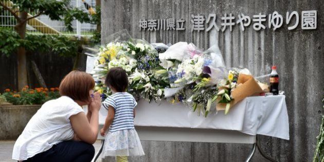 A mother and her daughter offer flowers for the victims of a knife rampage at the main entrance to the Tsukui Yamayuri En care centre in Sagamihara, Kanagawa prefecture on July 28, 2016.A man, who had threatened attacks on disabled people, went on a knife rampage on July 26 at the care centre where he previously worked, leaving 19 people dead in Japan's worst mass killing for decades. / AFP / KAZUHIRO NOGI (Photo credit should read KAZUHIRO NOGI/AFP/Getty Images)