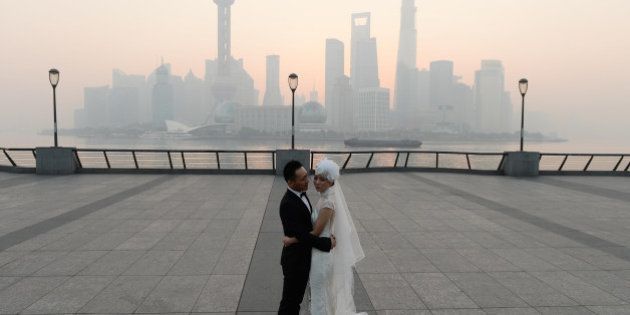 SHANGHAI, CHINA - NOVEMBER 07: (CHINA OUT) A newlywed couple takes wedding photos at the Bund as heavy smog engulfs the city on November 7, 2013 in Shanghai, China. People were advised to stay indoors today as the Shanghai Environment Agency measured air pollution levels at five out of a possible six. (Photo by ChinaFotoPress/ChinaFotoPress via Getty Images)