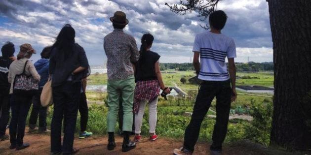 開沼博が開催しているスタディツアー「福島学構築プロジェクト」で仮置き場を見下ろしながら、語りべの話を聞く参加者（2014年6月）