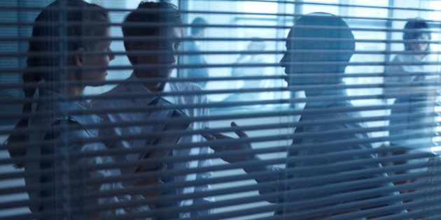 Three businesspeople talking behind the blinds