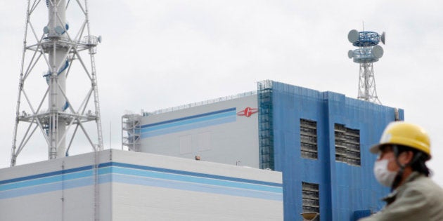 An employee cycles past Japan Atomic Power Co.'s Tokai Dai-Ni nuclear power station in Tokai Village, Ibaraki Prefecture, on Monday, Feb. 13, 2012. Japan Atomic Power Co. said on Oct. 14 it won't complete repairs of a nuclear station damaged in the March earthquake and tsunami till at least August this year. Photographer: Kiyoshi Ota/Bloomberg via Getty Images