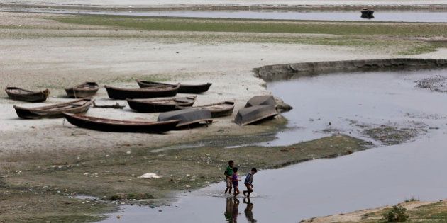 Indian children play near parked boats on the banks of river Ganges where water level has dried up in the summer in Allahabad, India, Wednesday, June 3, 2015. Light to moderate rainfall in various parts of the country brought respite from the scorching sun but heat wave claimed many lives in the southern Indian states of Andhra Pradesh and Telangana, raising the overall death toll to more than 2,000 since mid-April. (AP Photo/Rajesh Kumar Singh)