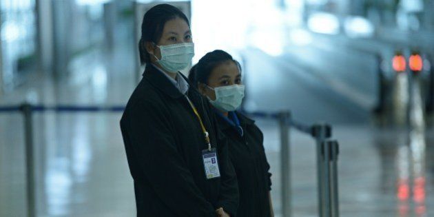 Airports of Thailand employees wear face masks as they wait for travelers to walk past a thermoscan checking their body temperature on arrival at Bangkok's Suvarnabhumi Airport on June 19, 2015. Thailand on June 18 said a 75-year-old man from Oman was confirmed to have MERS in Southeast Asia's first case of the virus since an outbreak in South Korea that has killed 23 people. AFP PHOTO / Christophe ARCHAMBAULT (Photo credit should read CHRISTOPHE ARCHAMBAULT/AFP/Getty Images)
