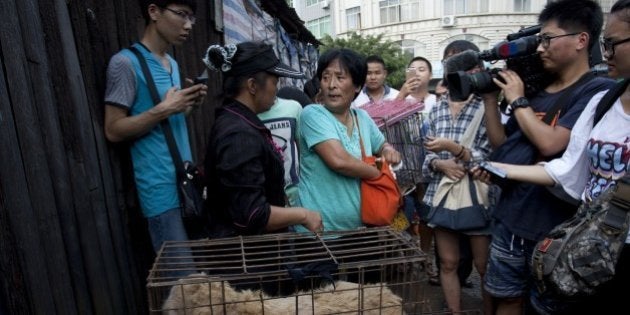 This picture taken on June 20, 2015 shows animal-loving Yang Xiaoyun (C) going around buying some 100 dogs at a market in Yulin, in southern China's Guangxi province. Yang has paid more than 1,000 USD to prevent around 100 canines from being eaten ahead of a dog meat festival which has provoked outrage worldwide. CHINA OUT AFP PHOTO (Photo credit should read STR/AFP/Getty Images)