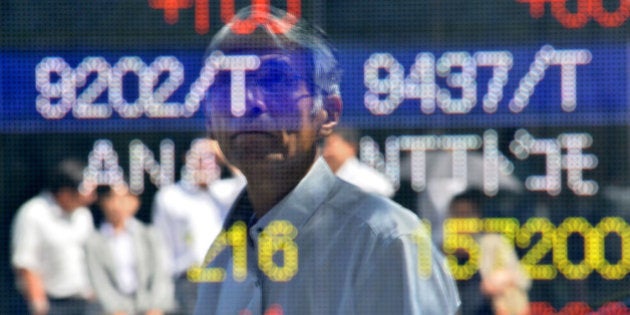 A pedestrian is reflected in the window as he looks at a quotation board flashing the Nikkei key index of the Tokyo Stock Exchange (TSE) on September 18, 2013. Tokyo stocks rose 1.81 percent in morning training on September 18, encouraged by gains on Wall Street as investors await the outcome of a Federal Reserve policy meeting. AFP PHOTO / KAZUHIRO NOGI (Photo credit should read KAZUHIRO NOGI/AFP/Getty Images)