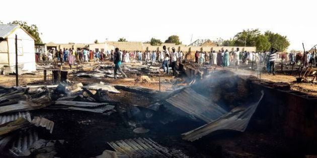 Residents of the Muna camp, near Maiduguri, gather near the site of an explosion on March 22, 2017. At least four suicide bomb blasts rocked a camp for migrants fleeing Boko Haram insurgents in restive northeastern Nigeria, killing at least three people and wounding 20, officials said. The blasts triggered fires which burned down tents in the vast Muna camp on the outskirts of the city of Maiduguri. / AFP PHOTO / STRINGER (Photo credit should read STRINGER/AFP/Getty Images)