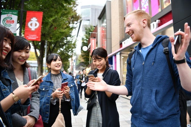 路上で出会った旅行者らと話すヤバタン＝東京・表参道