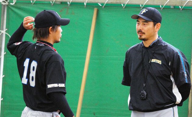 ブルペンで、ヤクルトから日本ハムに移籍した藤井秀悟（左）を指導する吉井理人投手コーチ（沖縄・名護市）
